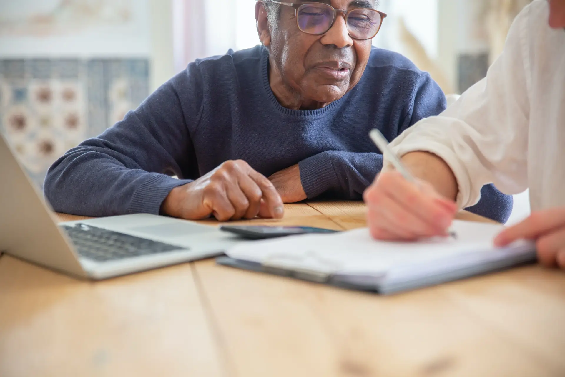 Person writing notes on clipboard speaking to another person