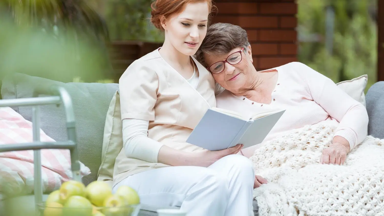 Enfermera leyendo a una paciente de cuidados paliativos